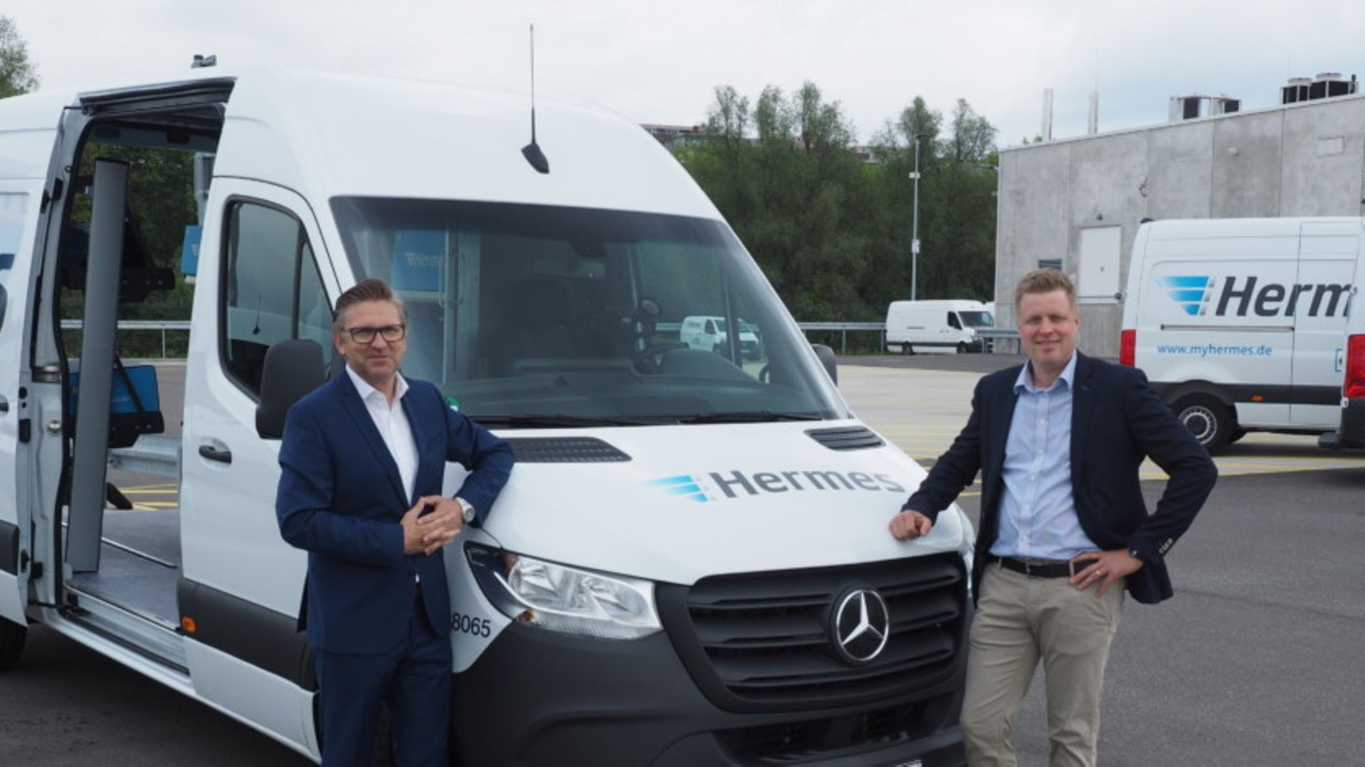 Pressefoto: Marco Schlüter und Olaf Lubenau stehen vor einem E-Transporter mit der Aufschrift Hermes